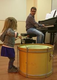 Luis al piano y una niña de corta edad tocando un tambor